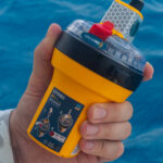The New Ocean Signal rescueME EPIRB3 with AIS Emergency Position Indicating Radio Beacon held in hand up close