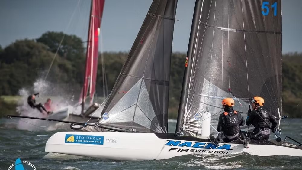 Two helmeted sailors on a Nacra F18 Evolution racing catamaran, pictured in Ocean Signal’s PLB3 rescue account