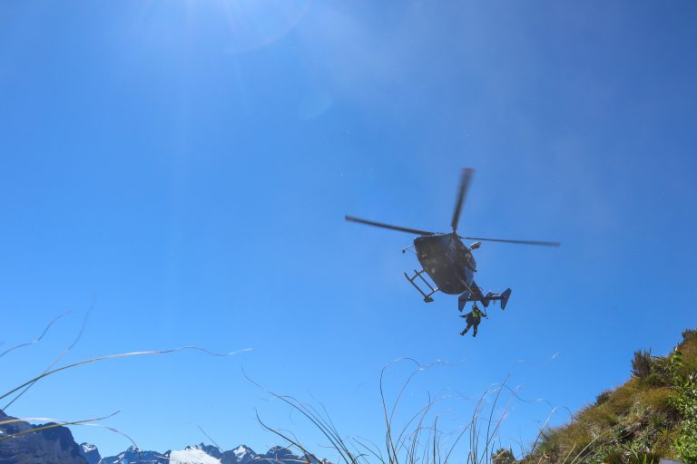 Rescue helicopter lifting an injured hiker and medic from the mountainside on the Routeburn Track
