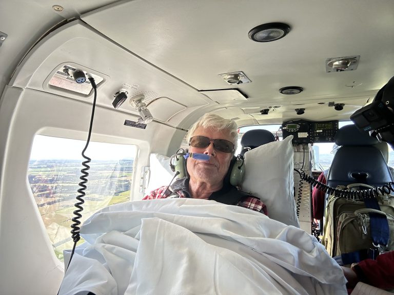 Gary wearing a headset and covered with a blanket inside the rescue helicopter after his Broken River emergency